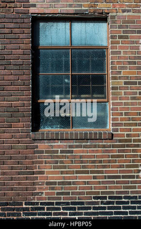 Brick wall with old broken window in natural light. Stock Photo