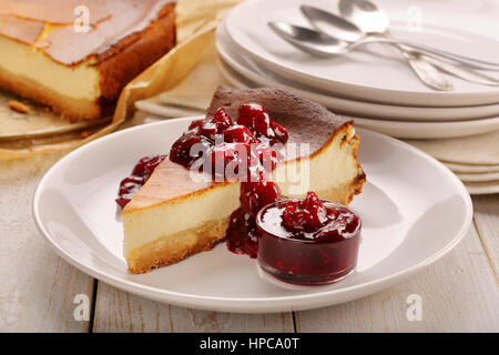 Cheesecake slice with cherry jam on wooden background Stock Photo