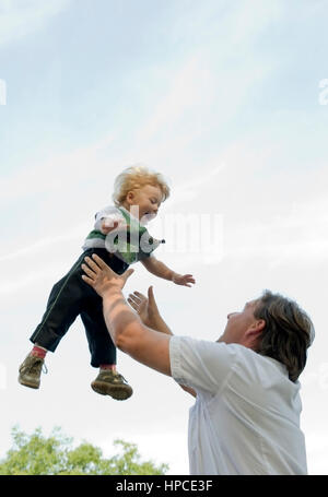 Model released , Vater wirft kleinen Jungen in die Luft - father throws sun in the sky Stock Photo