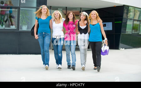 Model released , Fuenf jugendliche Maedchen spazieren Arm in Arm vor einem Gebaeude - five teenage girls walking Stock Photo