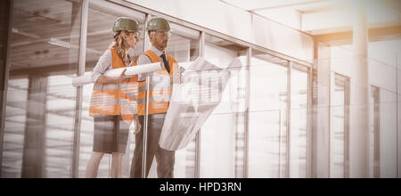 Architects discussing with blueprint in office corridor Stock Photo