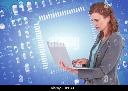 Businesswoman typing on laptop computer against blue micro electronic circuit Stock Photo