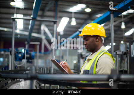 Factory worker writing on the clipboard in factory Stock Photo