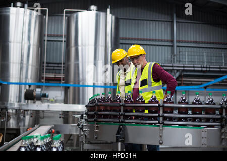 Two factory workers monitoring cold drink bottles at drinks production plant Stock Photo