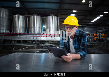 Factory worker using digital tablet at drinks production factory Stock Photo