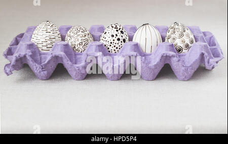 Decorating Easter eggs using a traditional wax-resist method and modern patterns. Eggs in a purple paper box with molten wax applied to the white shel Stock Photo