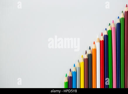 Colored pencils arranged in diagonal line on white background Stock Photo