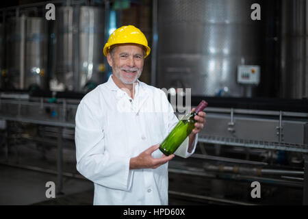 Portrait of factory worker examining a bottle in factory Stock Photo