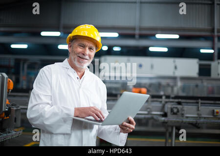 Portrait of factory engineer using laptop in drinks production plant Stock Photo