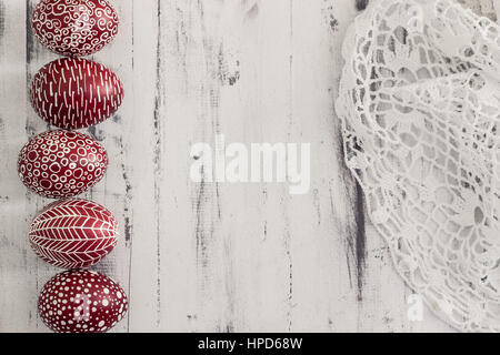 Decorated Easter eggs using a traditional in Eastern Europe wax-resist method and modern patterns. Still life with Pysanka, dry plants and lace on whi Stock Photo
