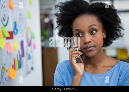 Female graphic designer talking on mobile phone in creative office Stock Photo