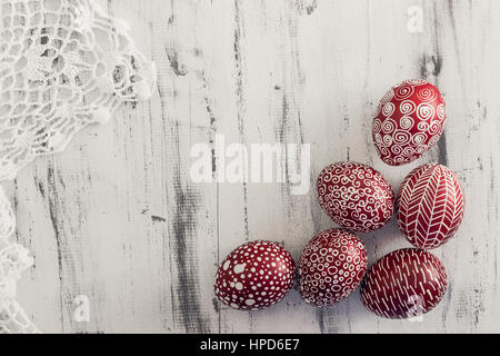 Decorated Easter eggs using a traditional in Eastern Europe wax-resist method and modern patterns. Still life with Pysanka, dry plants and lace on whi Stock Photo