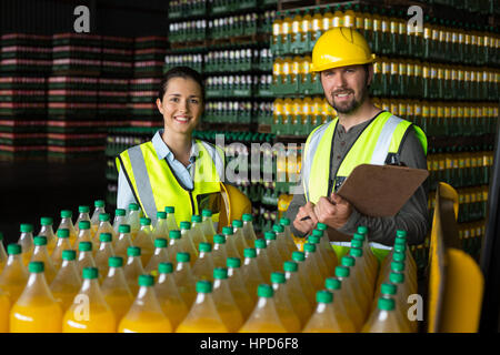 Portrait of two factory workers monitoring cold drink bottles at drinks production factory Stock Photo
