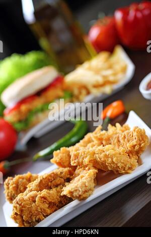 Breaded chicken strips with sauces, tomatoes, peppers. Stock Photo