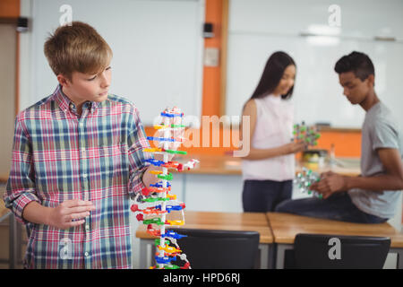 Schoolboy examining molecule model in laboratory at school