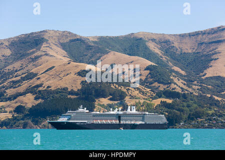 Akaroa, Canterbury, New Zealand. The Holland America Line cruise ship Oosterdam anchored in Akaroa Harbour beneath the hills of the Banks Peninsula. Stock Photo