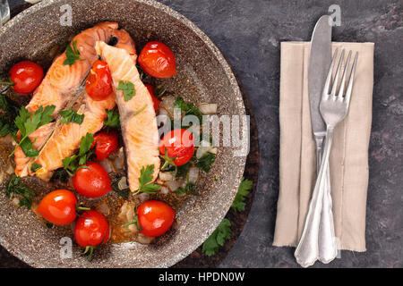 Closeup shot of fried salmon steak with lemon and vegetables on frying pan. Stock Photo