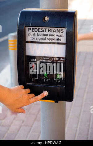 Woman finger pushing pedestrians button to cross the street. Stock Photo