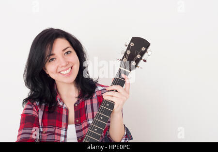 Pretty young girl holding an acoustic guitar neck, looking at the camera and smiling Stock Photo