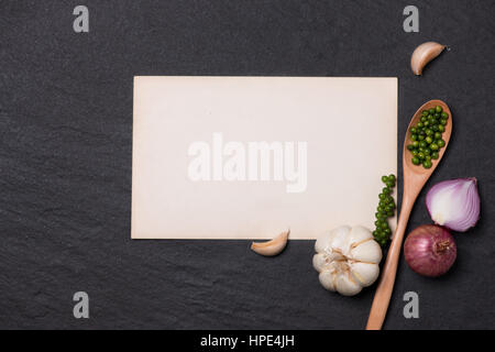 Vegetable recipe. Open menu book with fresh herbs and spices on dark background Stock Photo