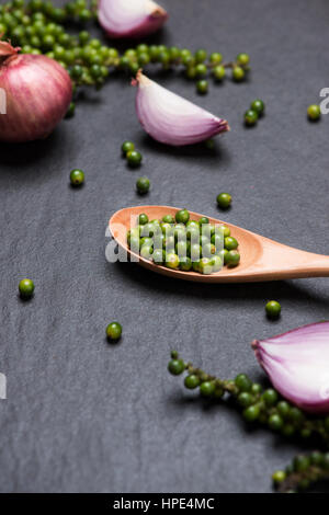 Fresh vegetables on black table. Red onion rings and green peppercorns. Top view. Stock Photo
