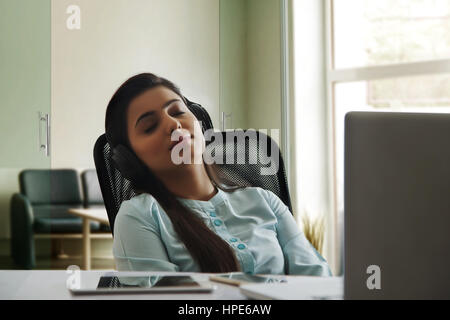 Relaxed businesswoman listening music in office Stock Photo