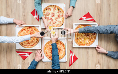 Group of friends having a pizza party at home and enjoying together, they are toasting with drinks, flat lay Stock Photo