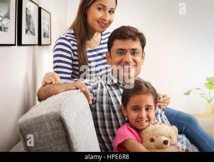 Portrait of happy young family sitting in sofa Stock Photo