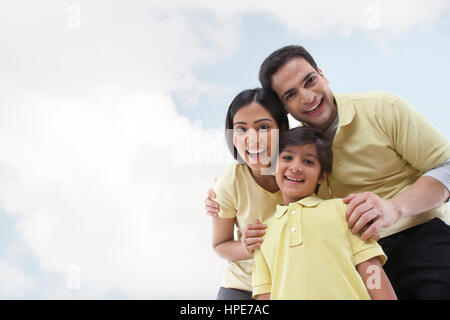 Portrait of a happy family looking at the camera against sky and clouds Stock Photo