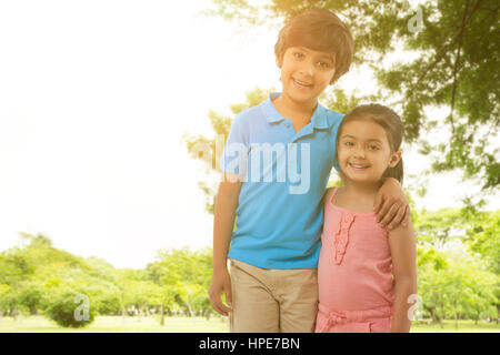 Portrait of brother and sister standing arm around in park Stock Photo