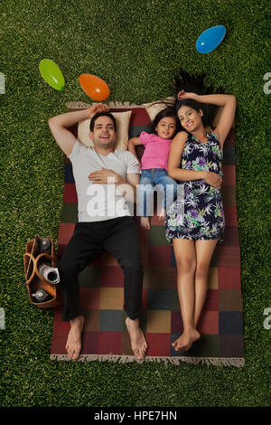 Couple and young daughter lying on picnic blanket Stock Photo