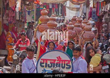 Women bearing symbolic bowls on their heads in a procession making its way through the streets of Deogarh in rajasthan as part of wedding celebrations Stock Photo