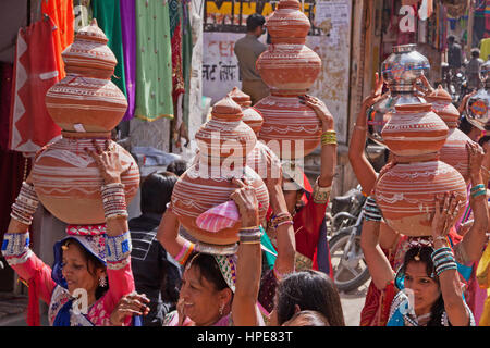 Women bearing symbolic bowls on their heads in a procession making its way through the streets of Deogarh in rajasthan as part of wedding celebrations Stock Photo