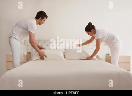 Young couple making bed Stock Photo