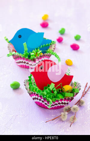 Easter decorations children's table. Easter table decoration nest with baby bird paper and candy, painted quail eggs. Copy space. Stock Photo