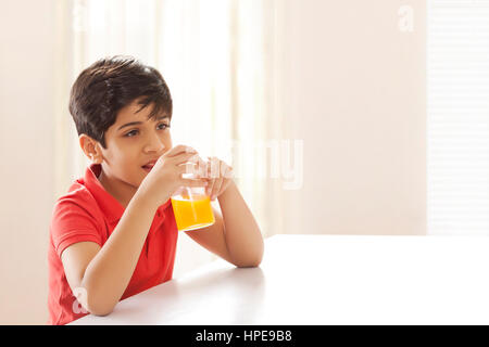 Boy drinking juice sitting at dining table Stock Photo