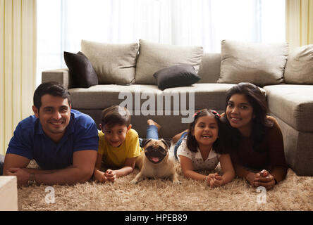 Happy family with pug posing on carpet in living room Stock Photo