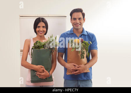 Young couple holding groceries bag standing in front of refrigerator Stock Photo