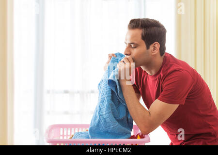 Young man smelling clean towels in laundry Stock Photo