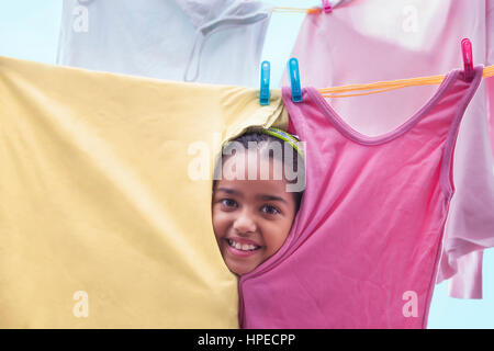 Young girl peeking through cloths on a clothesline Stock Photo
