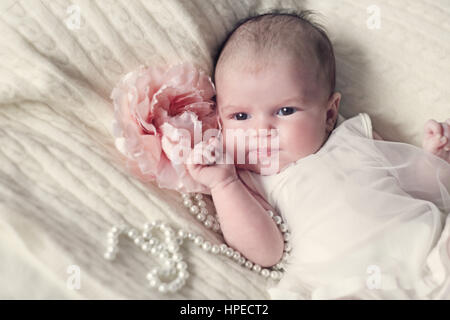 Newborn baby girl in fshionable dress with flower and pearl beads Stock Photo