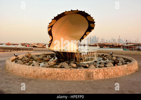 Doha, Qatar - November 2, 2016. Pearl monument in Doha, with people, cars, boats and buildings in the background, at dawn Stock Photo