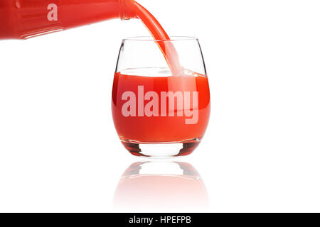 Tomato juice is flowing into a glass isolated on white background Stock Photo