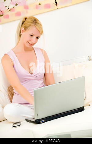 Model released , Junge Frau, 35, mit Laptop auf der Couch - woman using laptop at home Stock Photo