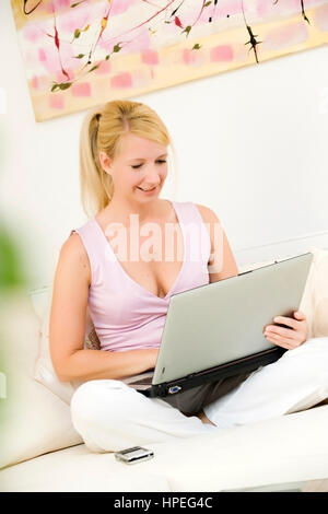 Model released , Junge Frau, 35, mit Laptop auf der Couch - woman using laptop at home Stock Photo