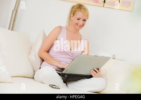 Model released , Junge Frau, 35, mit Laptop auf der Couch - woman using laptop at home Stock Photo