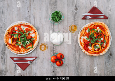 Tasty pizza on a rustic table and ingredients composing the italian flag, mediterranean eating concept Stock Photo