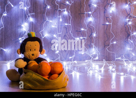 funny monkey toy with oranges under the lights Stock Photo