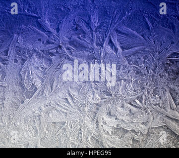 macro of Ice patterns on winter window glass with blue gradient Stock Photo
