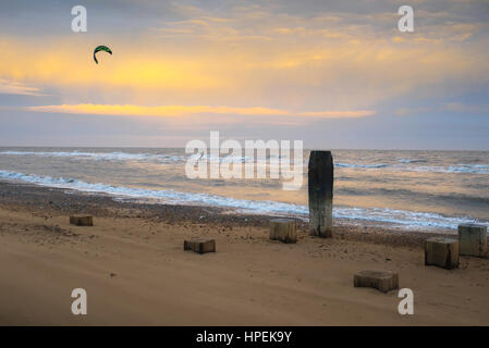 Kite surfing sea, view of a kite surfer skimming the waves at dusk along the beach at Lowestoft in Suffolk, England UK. Stock Photo